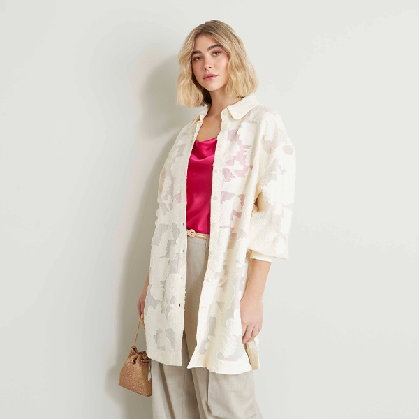 Modella indossa camicia con ricamo abbinata a top di colore fucsia