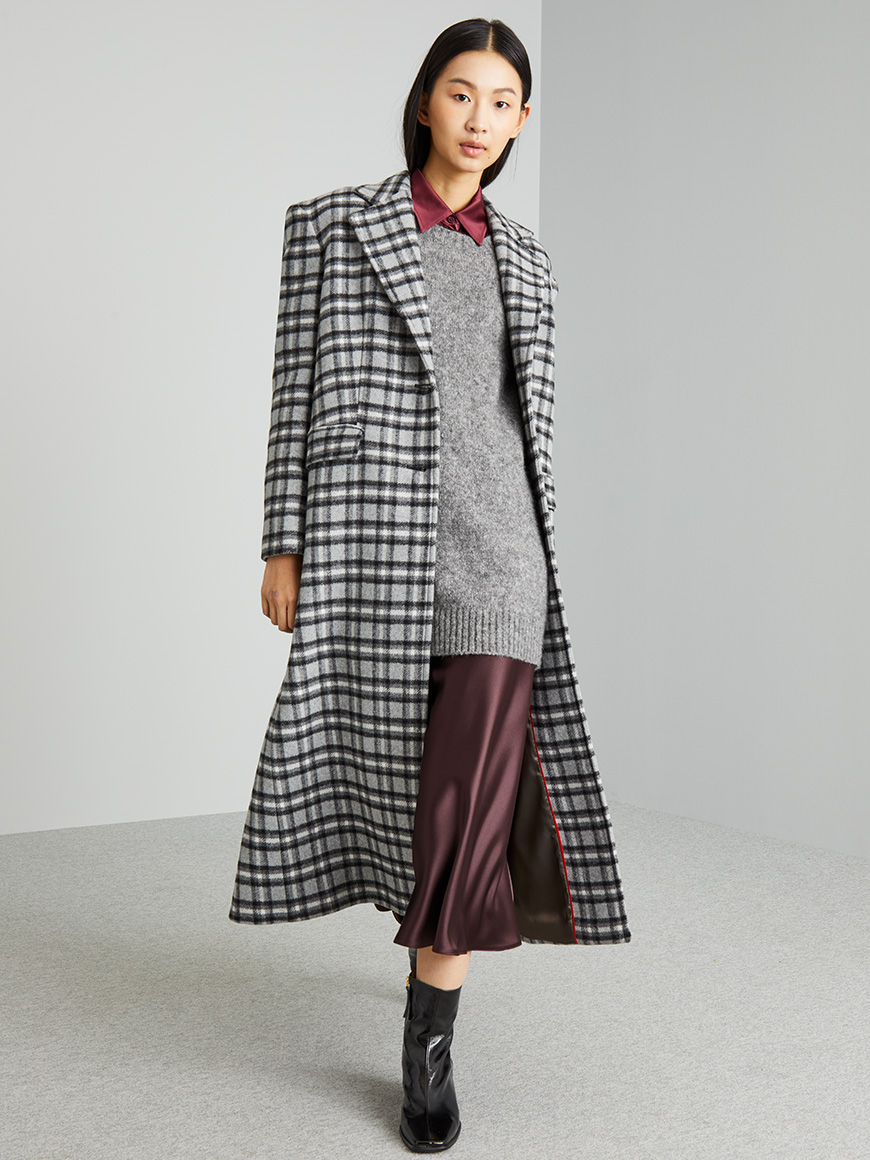 Modella indossa cappotto tartan bianco e nero.