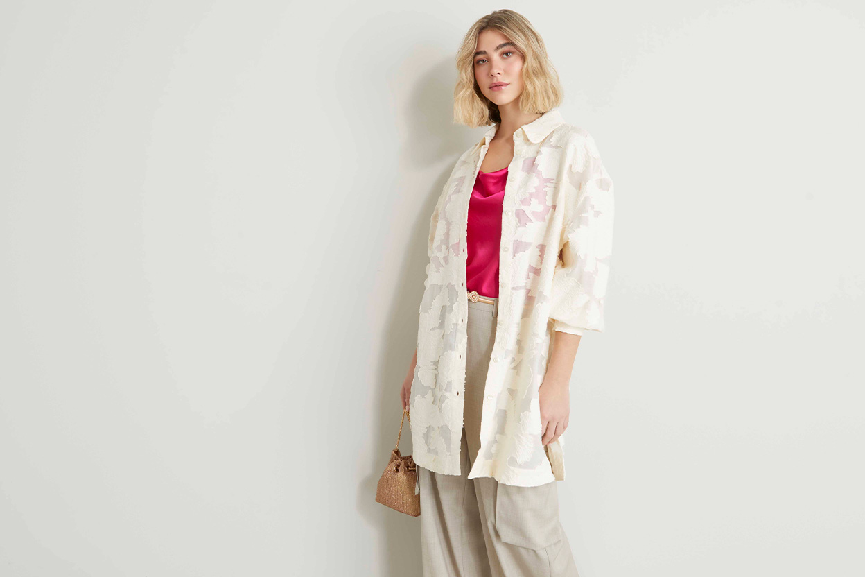 Modella indossa camicia con ricamo abbinata a top di colore fucsia